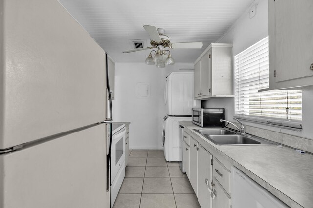 kitchen with white appliances, a ceiling fan, light tile patterned flooring, light countertops, and stacked washer and dryer
