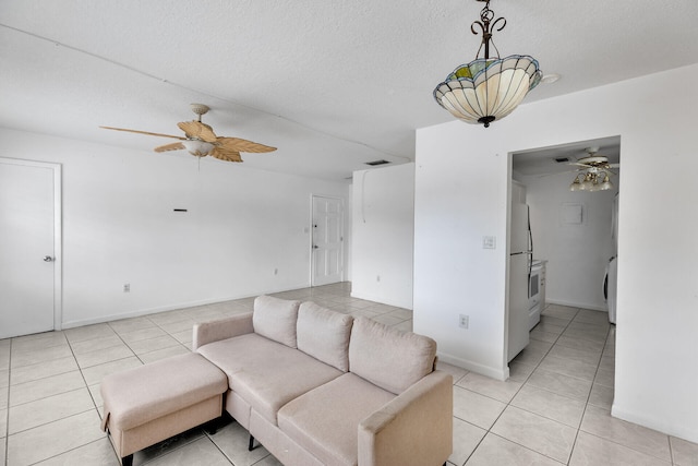 living area with visible vents, a ceiling fan, a textured ceiling, light tile patterned flooring, and baseboards