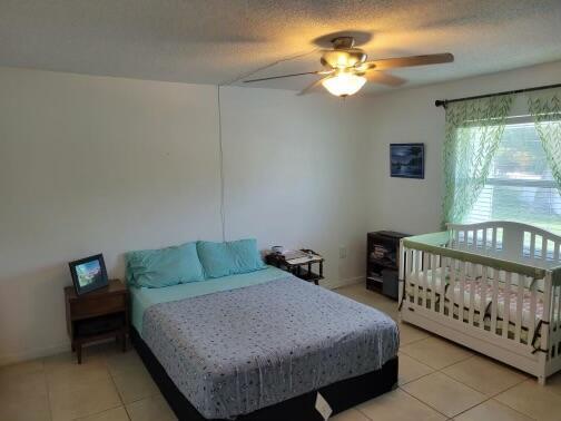 bedroom featuring ceiling fan, a textured ceiling, and light tile patterned floors