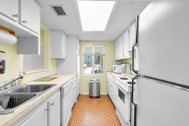 kitchen with visible vents, white cabinetry, white appliances, light countertops, and light floors