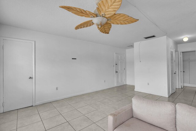 unfurnished living room featuring light tile patterned floors, visible vents, baseboards, and a textured ceiling
