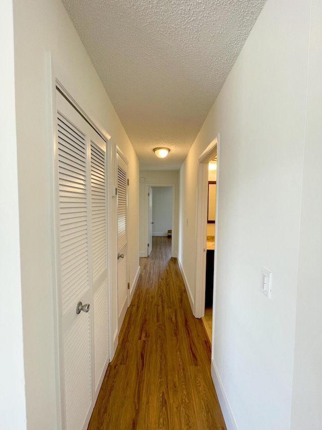 hall with hardwood / wood-style flooring and a textured ceiling