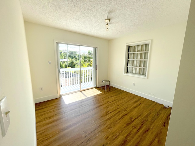 unfurnished room with hardwood / wood-style floors and a textured ceiling