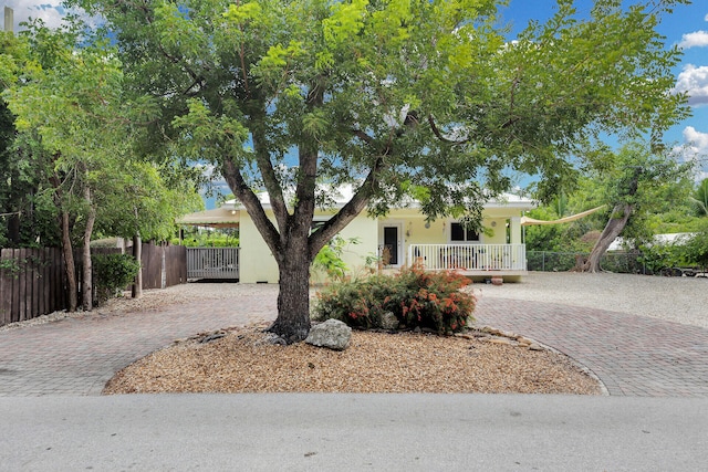 1 Sunset Rd, Key Largo, FL 33037 - view of front of home with decorative driveway, stucco siding, a fenced front yard, and covered porch