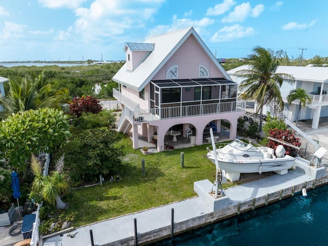 back of property featuring a balcony, a water view, a patio area, and a lawn