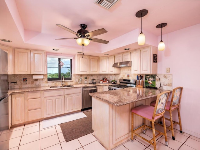 kitchen with sink, hanging light fixtures, stainless steel appliances, light stone countertops, and kitchen peninsula