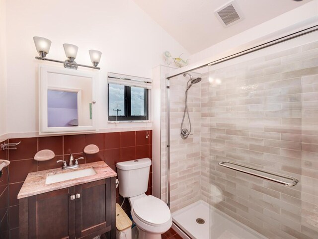 bathroom featuring lofted ceiling, toilet, an enclosed shower, tile walls, and vanity