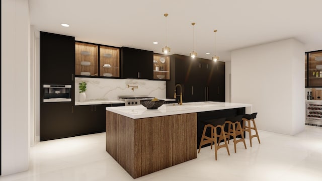 kitchen with decorative light fixtures, oven, backsplash, dark brown cabinetry, and a center island with sink