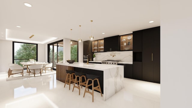 kitchen featuring pendant lighting, a breakfast bar, light stone counters, a center island with sink, and decorative backsplash