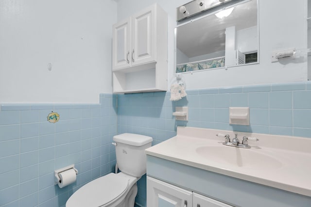 bathroom featuring vanity, toilet, and tile walls