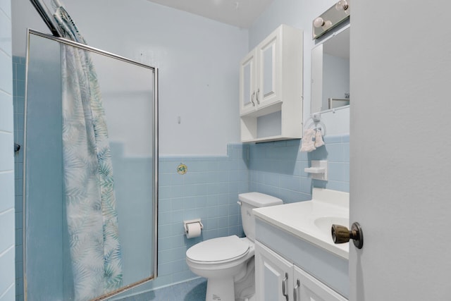 bathroom with tile walls, vanity, a shower, and toilet