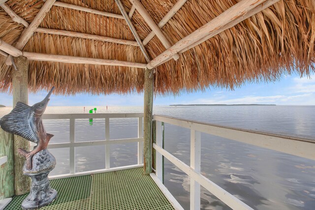 dock area with a gazebo, a beach view, and a water view