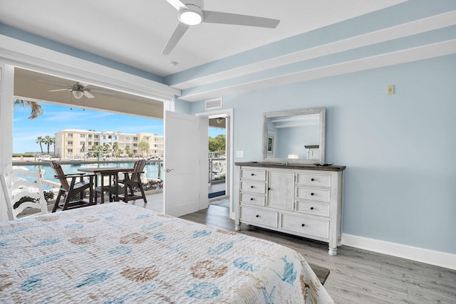 bedroom featuring hardwood / wood-style flooring, a water view, access to outside, and ceiling fan