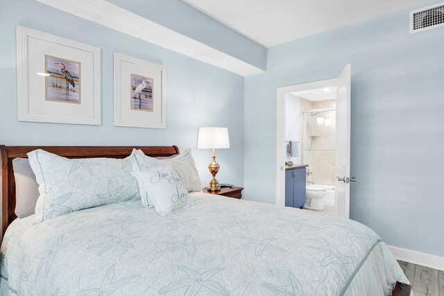 bedroom featuring ensuite bath and wood-type flooring