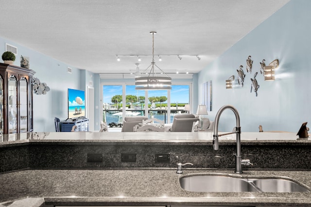 kitchen featuring pendant lighting, rail lighting, sink, and a textured ceiling