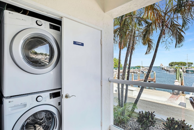 laundry room featuring stacked washing maching and dryer and a water view