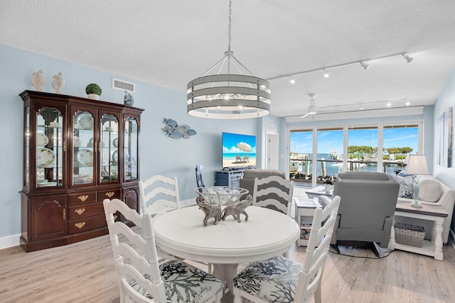 dining area featuring ceiling fan with notable chandelier, a textured ceiling, and light hardwood / wood-style flooring