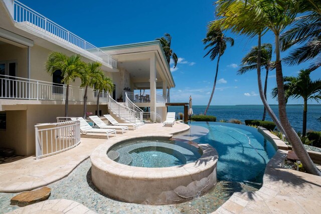 view of pool with an in ground hot tub, a water view, and a patio