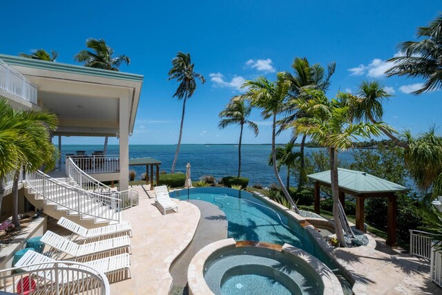 view of swimming pool featuring an in ground hot tub, a water view, a gazebo, and a patio area