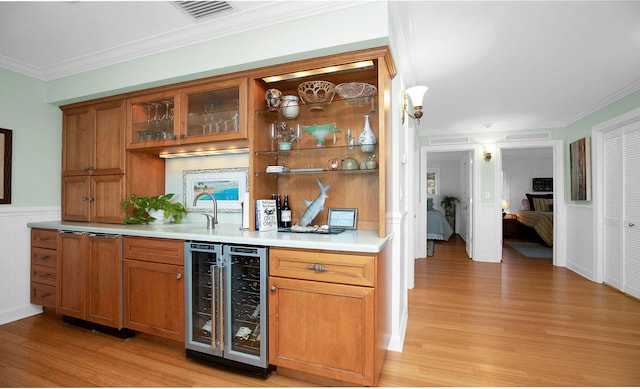 bar with wine cooler, ornamental molding, sink, and light hardwood / wood-style floors