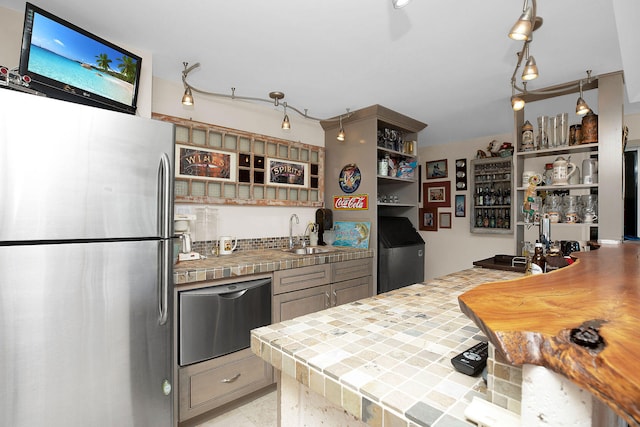 kitchen with sink, tile counters, and stainless steel fridge