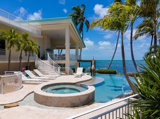 view of pool with an in ground hot tub, a water view, and a patio