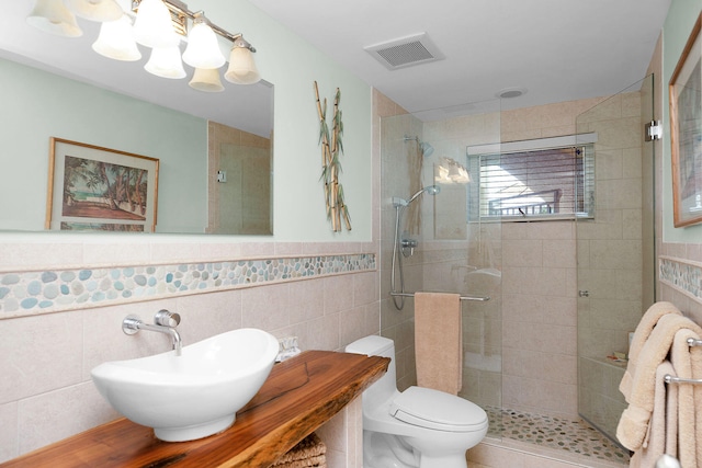 bathroom with tile walls, an enclosed shower, sink, and toilet