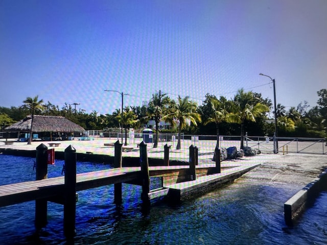 view of dock with a gate, fence, and a water view