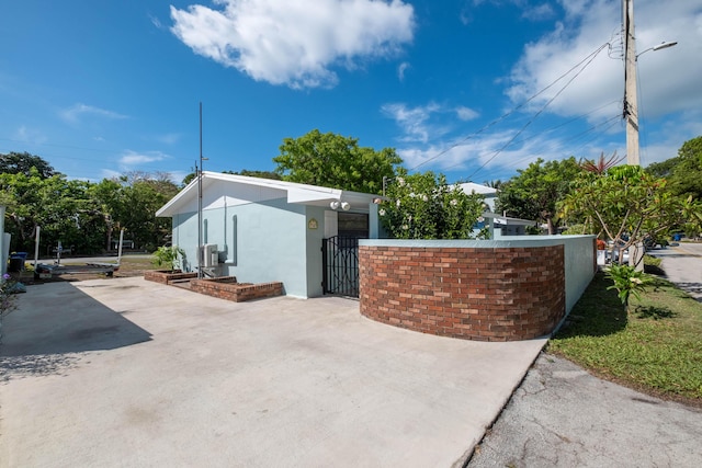 view of side of home featuring a gate, a patio area, a fenced front yard, and stucco siding