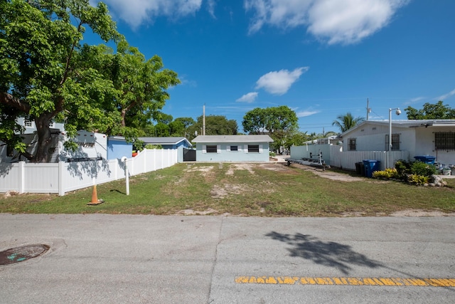 view of front of house with driveway, a front lawn, and fence