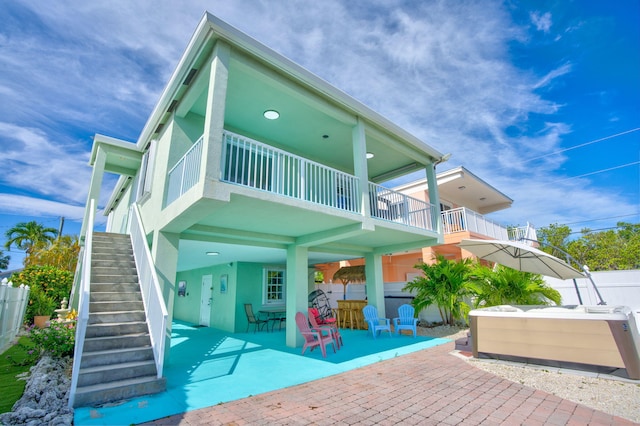 back of property with a jacuzzi, a patio area, and a balcony