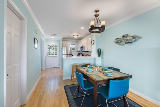 dining room with ornamental molding and light hardwood / wood-style flooring