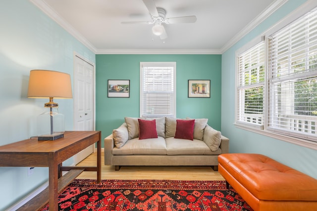 living room featuring plenty of natural light, ornamental molding, ceiling fan, and light wood-type flooring