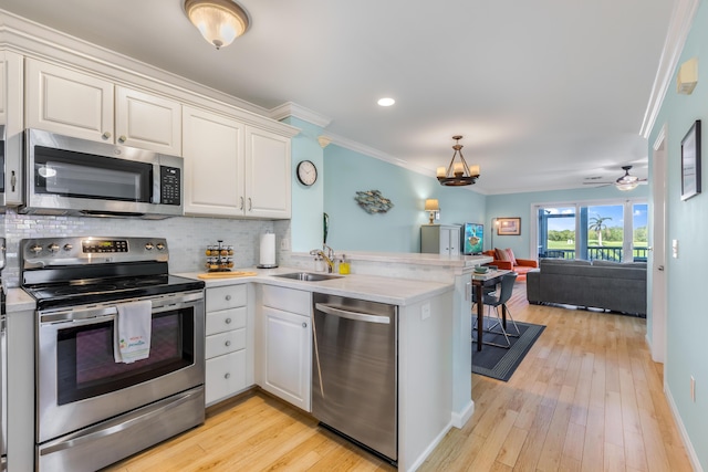 kitchen featuring stainless steel appliances, kitchen peninsula, sink, and white cabinets