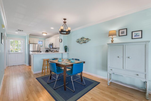 dining space featuring ornamental molding, light hardwood / wood-style floors, and a chandelier