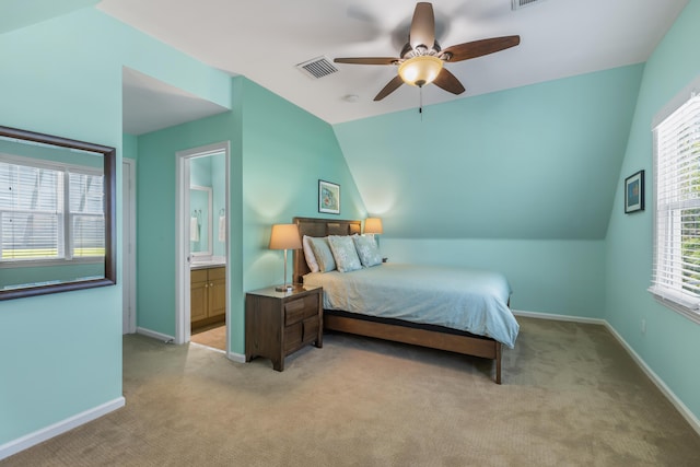 bedroom featuring ceiling fan, light colored carpet, lofted ceiling, and ensuite bathroom