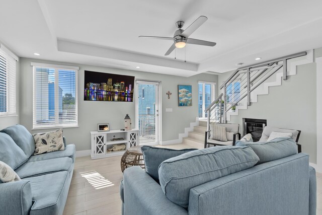 living room featuring a tray ceiling, plenty of natural light, light hardwood / wood-style floors, and ceiling fan