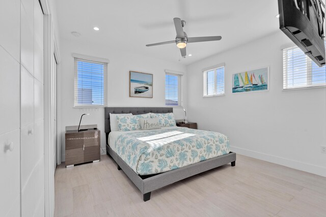 bedroom featuring multiple windows, light hardwood / wood-style flooring, a closet, and ceiling fan