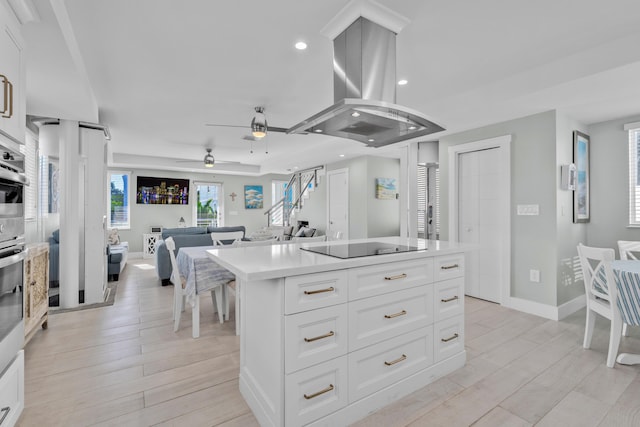 kitchen featuring island range hood, light wood-type flooring, white cabinets, and a kitchen island