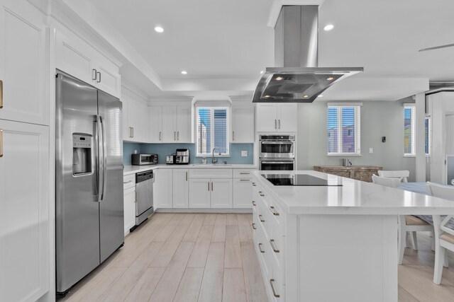 kitchen with white cabinets, appliances with stainless steel finishes, a center island, and island range hood