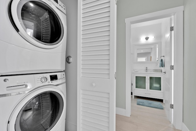 laundry room featuring stacked washer / dryer and light wood-type flooring