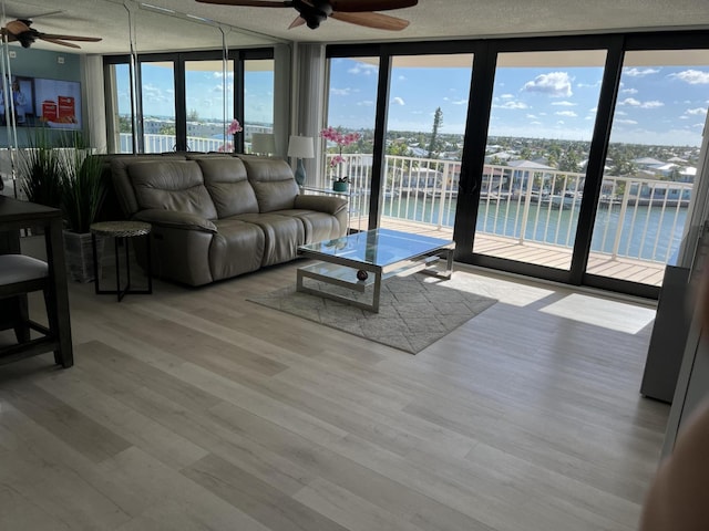 2000 Coco Plum Dr Unit 605, Marathon, FL 33050 - living area featuring a ceiling fan, a water view, a textured ceiling, wood finished floors, and expansive windows