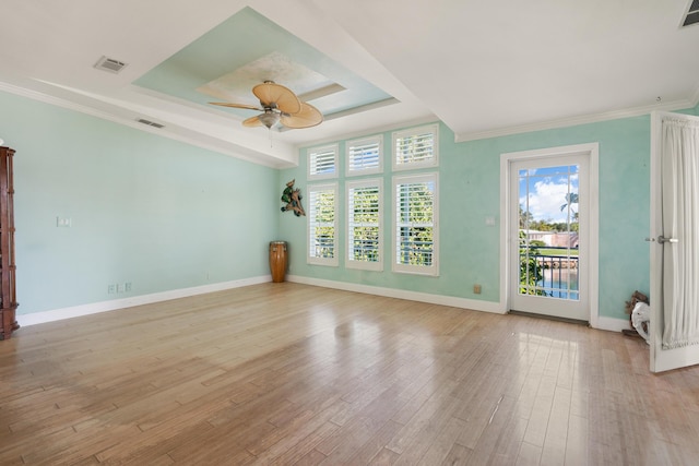 unfurnished room with ceiling fan, visible vents, baseboards, a tray ceiling, and light wood finished floors