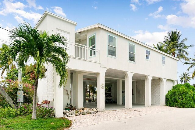 view of front facade featuring a carport, concrete driveway, a balcony, and stucco siding