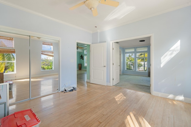 unfurnished room featuring light wood-style floors, plenty of natural light, and ornamental molding