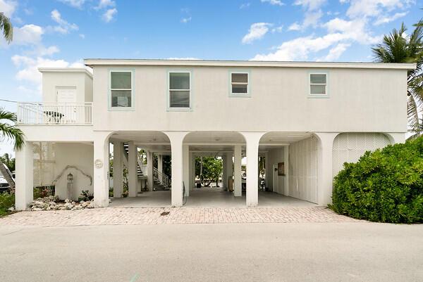 view of front facade with a carport, decorative driveway, stairway, and stucco siding