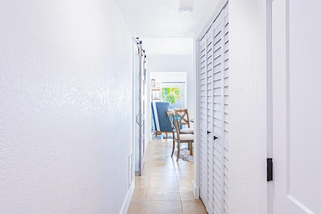 corridor featuring light tile patterned flooring and a barn door