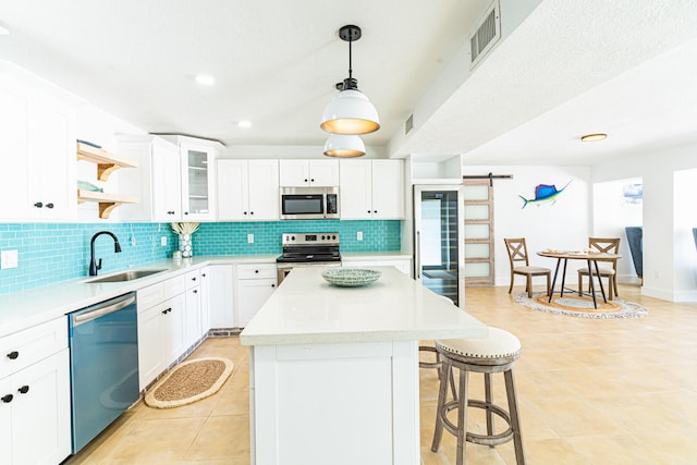 kitchen featuring a barn door, appliances with stainless steel finishes, sink, and white cabinets