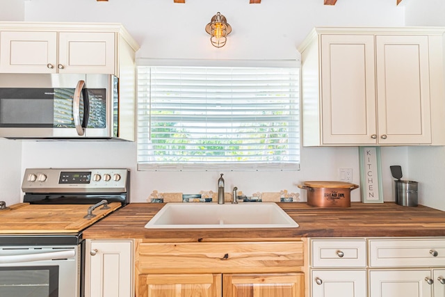 kitchen featuring stainless steel appliances, butcher block counters, and sink