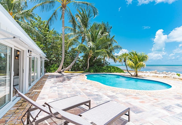 view of swimming pool featuring a patio and a water view